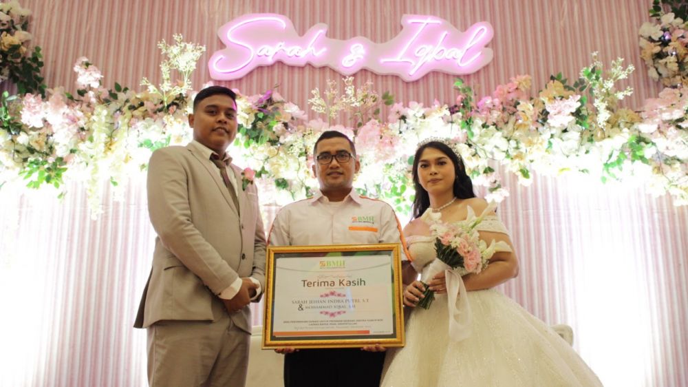 Pasangan pengantin menunjukkan piagam dari BMH