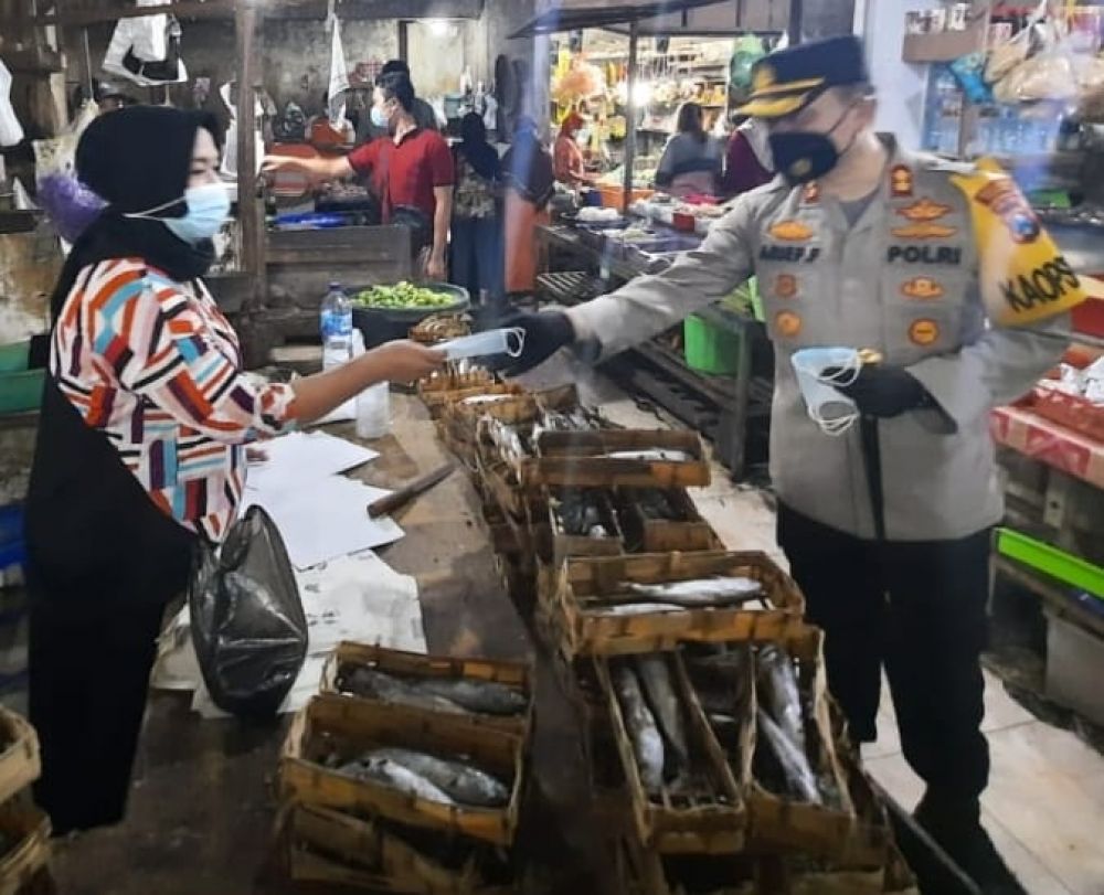Kapolres Gresik sedang berbagi masker ke pedagang dengan mengoptimalkan PPKM