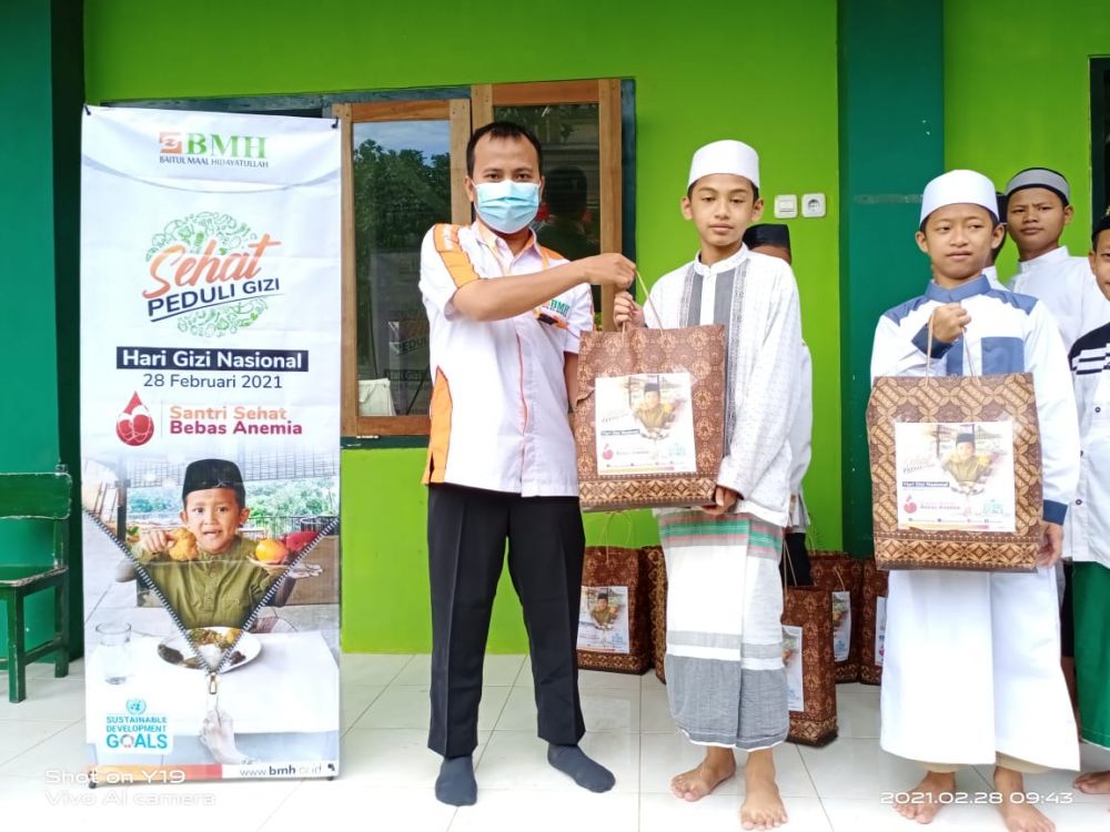 Petugas laznas BMH sedang membagikan paket gizi untuk santri dan dhuafa