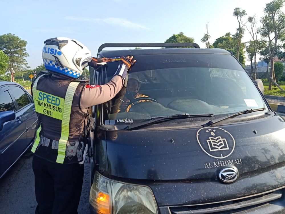 Satlantas Polres Gresik berbagi masker dan stiker pada R4 dan R2 yang lewat di jalan Raya