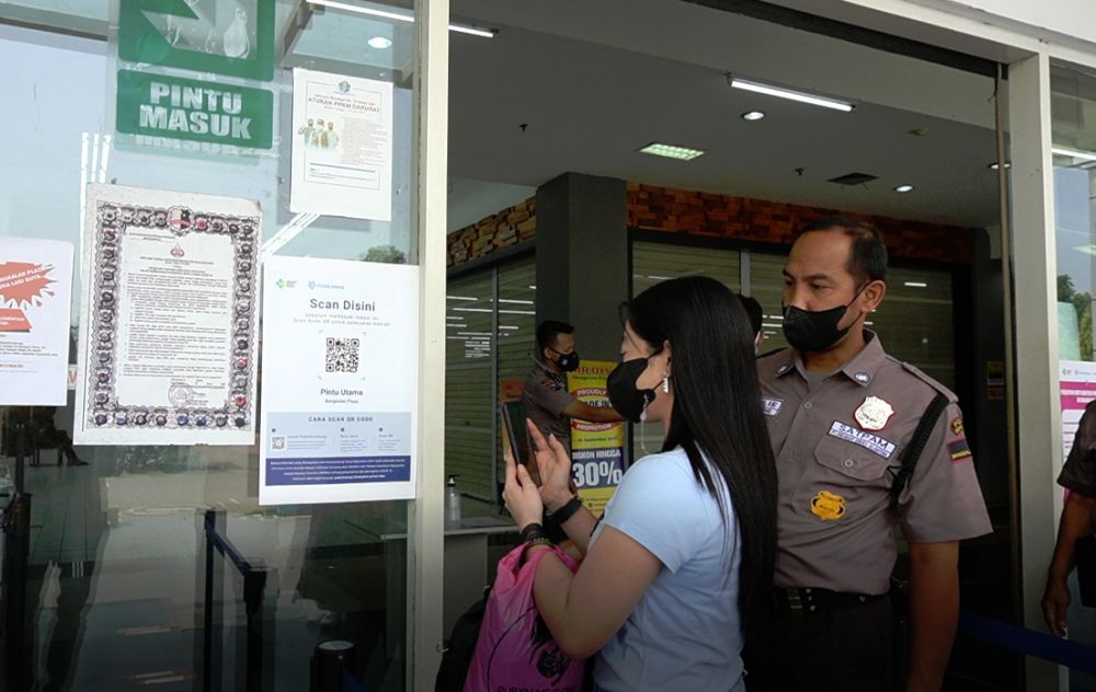 Warga yang menggunakan aplikasi PeduliLindungi saat memasuki tempat perbelanjaan
