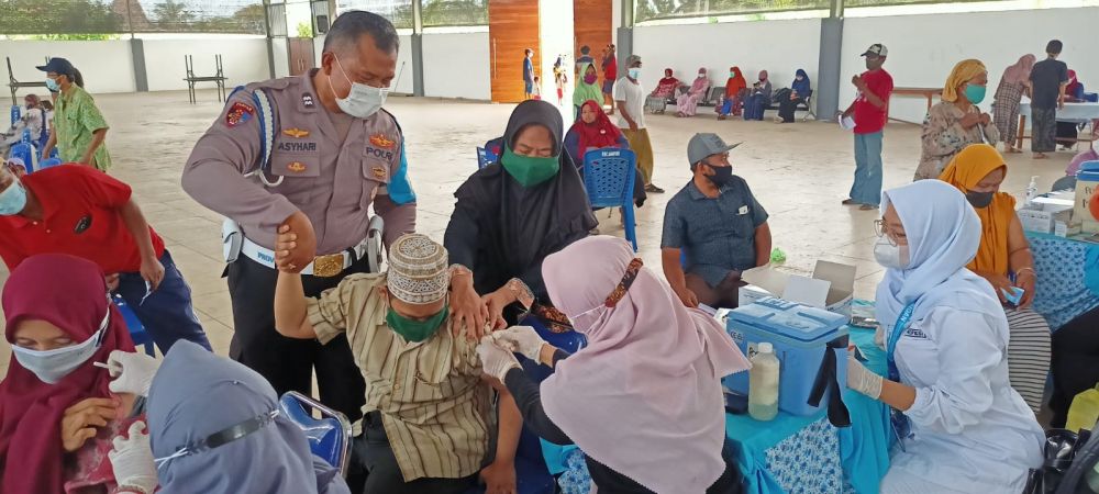 Petugas Kepolisian saat membantu anak Down Syndrome yang menerima vaksin