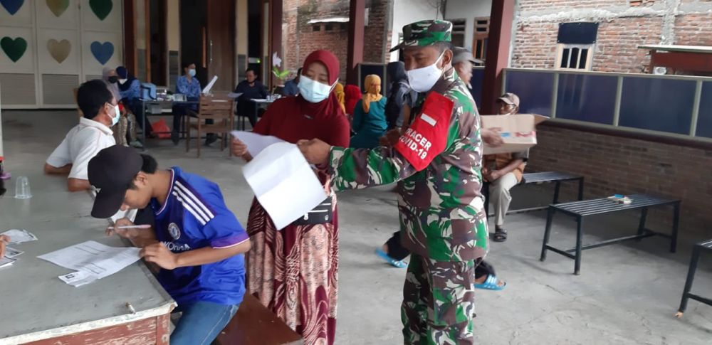 Babinsa Koramil Menganti saat memberikan arahan warga binaan proses vaksinasi