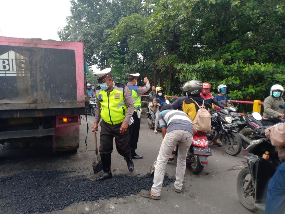 Polantas Driyorejo saat membantu pekerja mempercepat pengaspalan