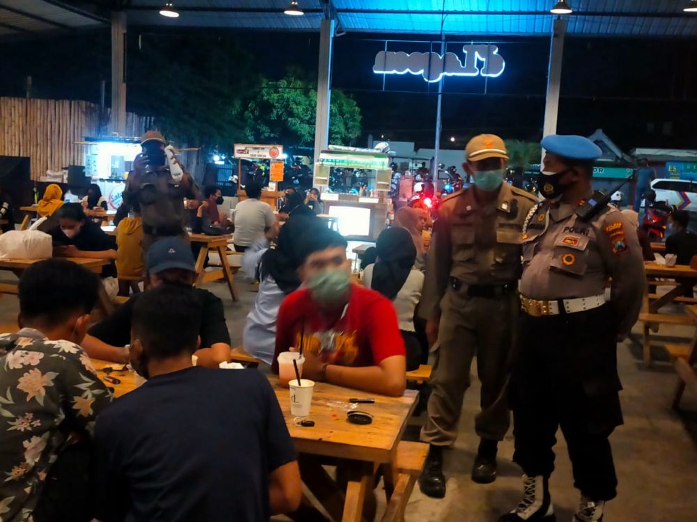Tim Pamor Keris gabungan Polres Gresik saat memberikan edukasi Protokol Kesehatan pengunjung Cafe dan warkop plus bagikan masker