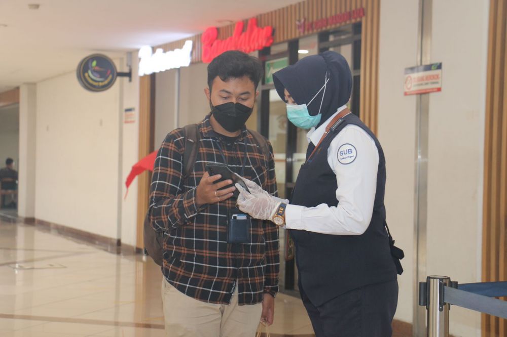 Penumpang bandara Juanda saat menunjukkan aplikasi PeduliLindungi ke petugas bandara Juanda 