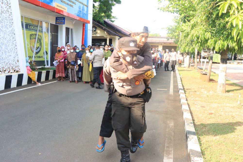 Briptu Wira saat gendong warga disabilitas menerima penyaluran BTPKLWN