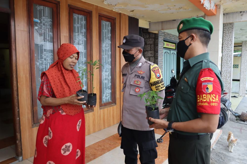 Bhabinkamtibmas Polsek Manyar bersama Babinsa Koramil 0817/06 Manyar saat memberikan bibit cabai ke warga